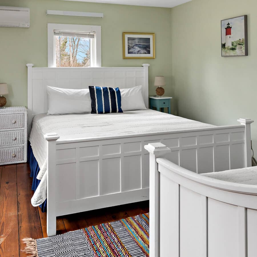 A cozy, softly lit bedroom featuring a white bed, colorful accent pillows, and a patterned rug.