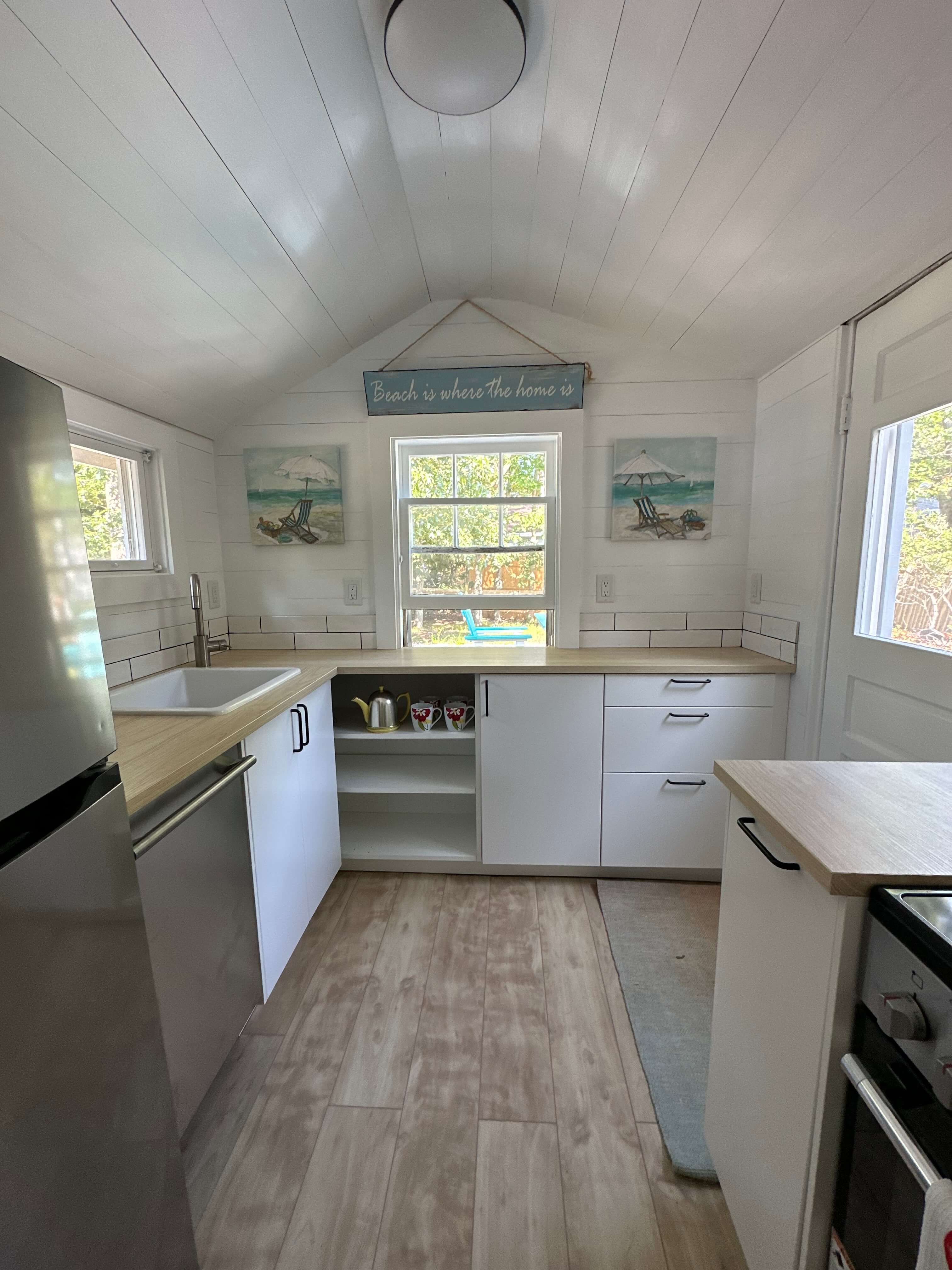 Bright, modern kitchen featuring white cabinetry, wood countertops, and beach-themed decor.