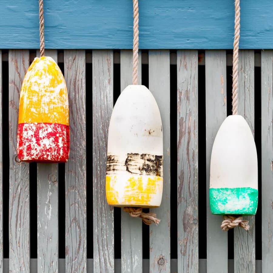Three colorful buoys hanging from a wooden wall.