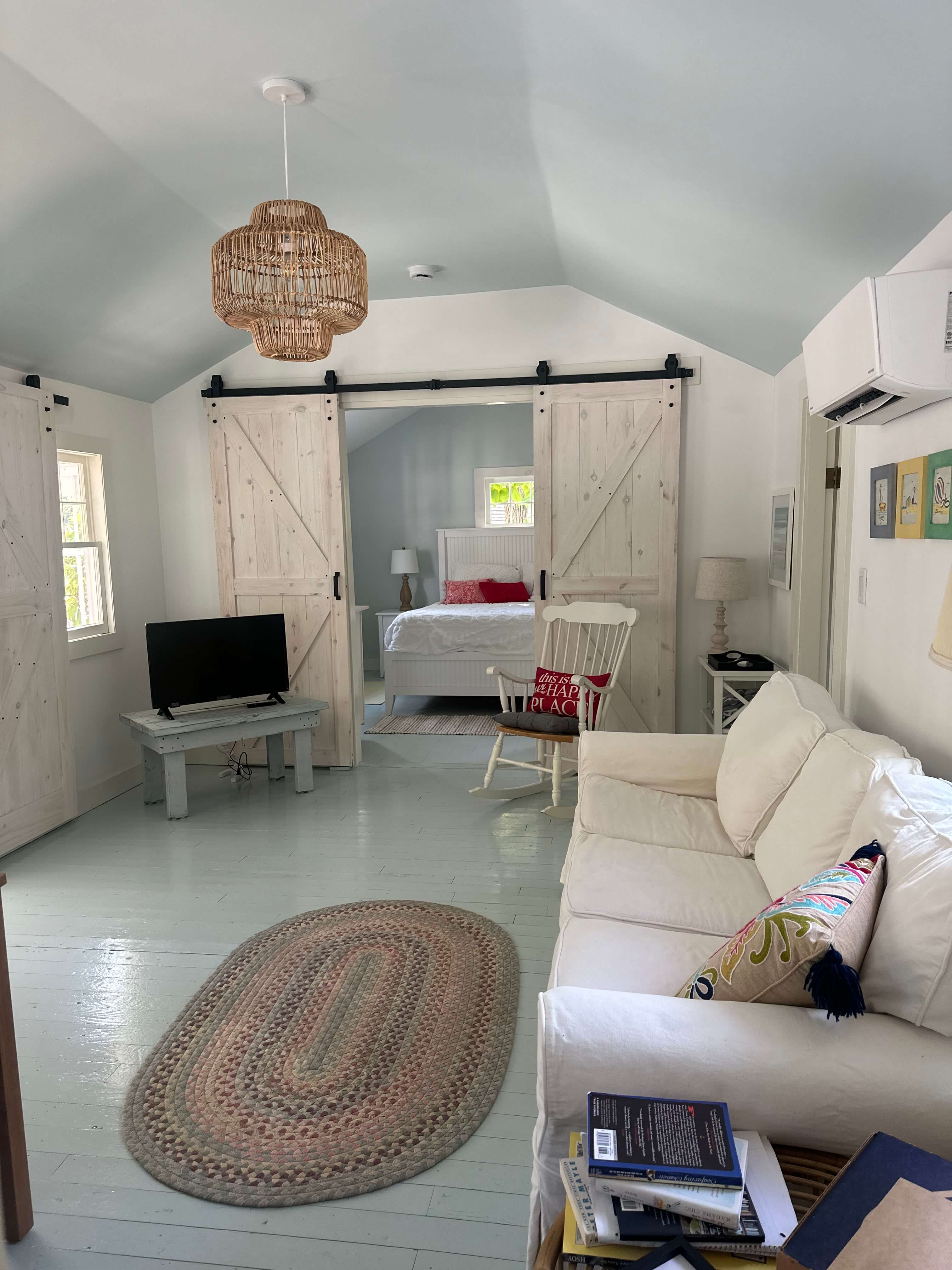 Cozy living space featuring a white sofa, TV, sliding barn doors, and a view of a bedroom.