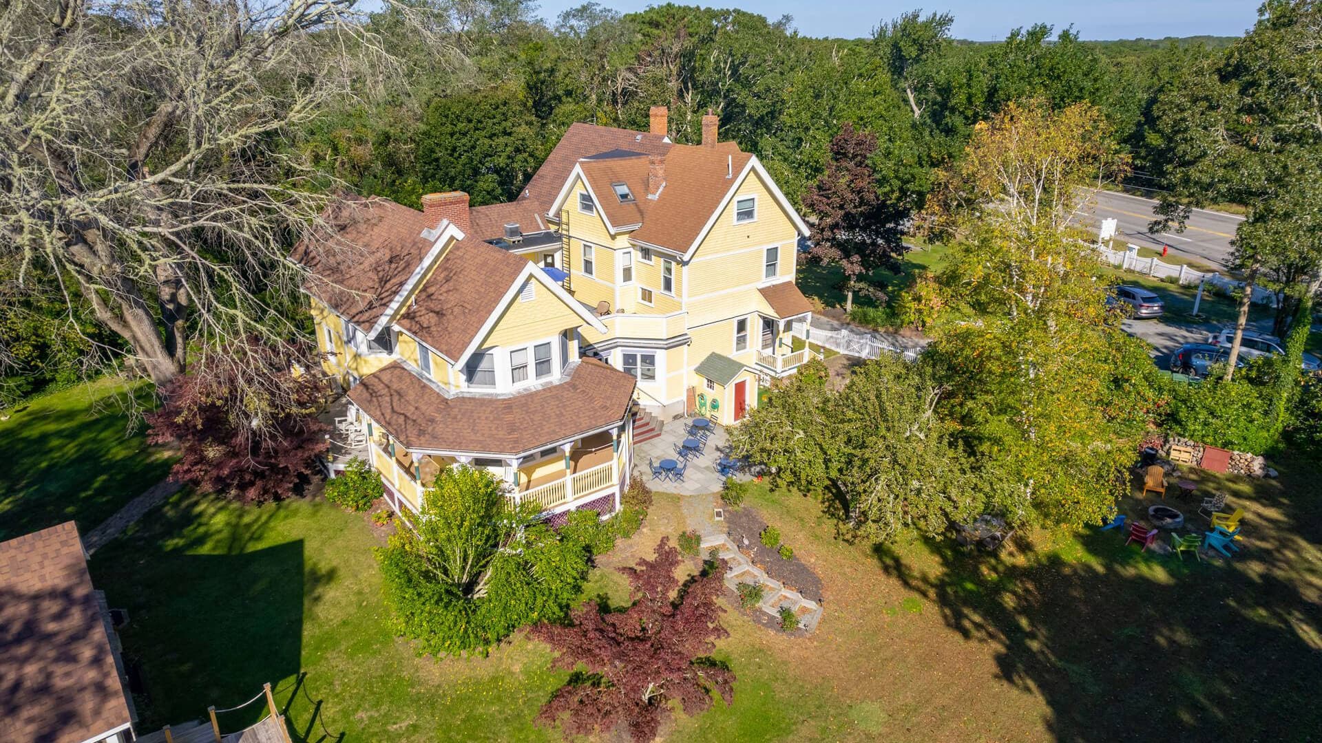 Aerial view of a large yellow Victorian-style house surrounded by greenery.