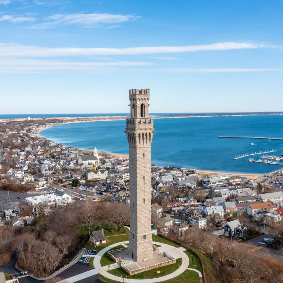 Aerial view of a tall stone tower overlooking a coastal town and harbor.