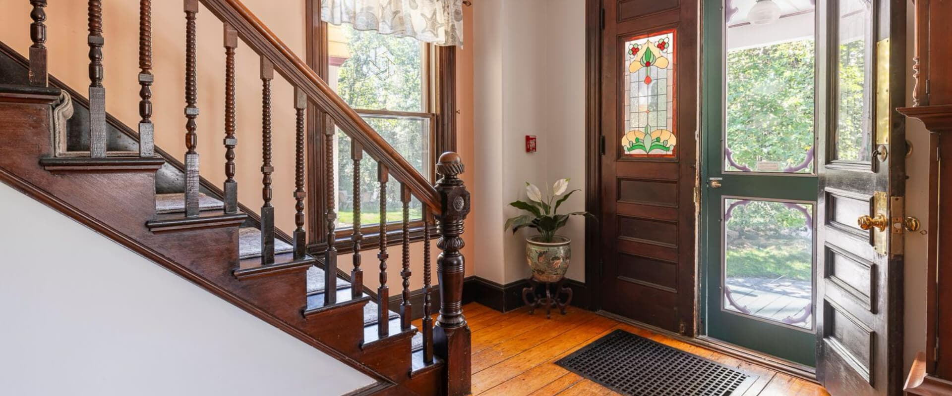 Interior view of a foyer with a staircase and a decorative front door.